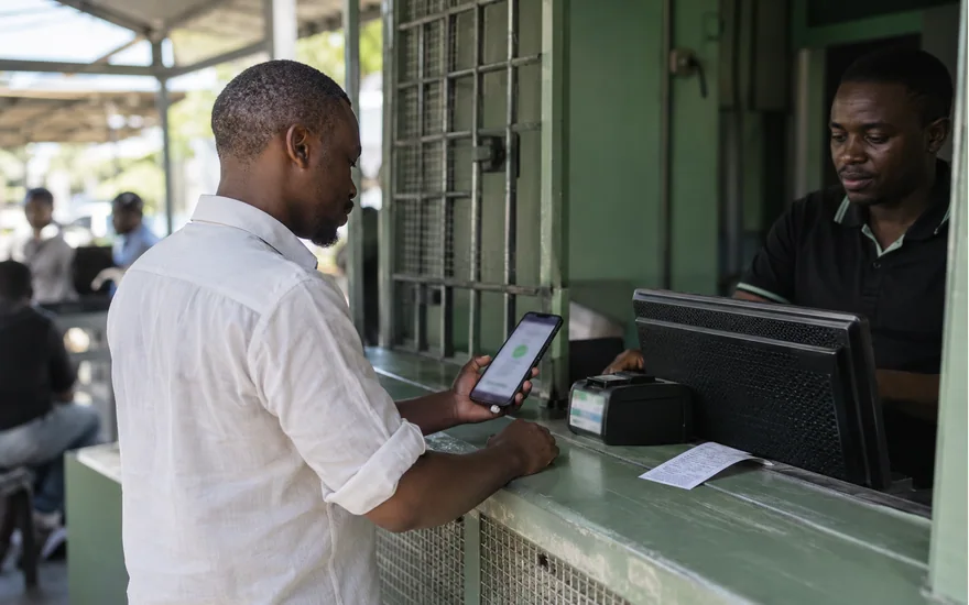 Customer checking a phone at a green mobile money service counter